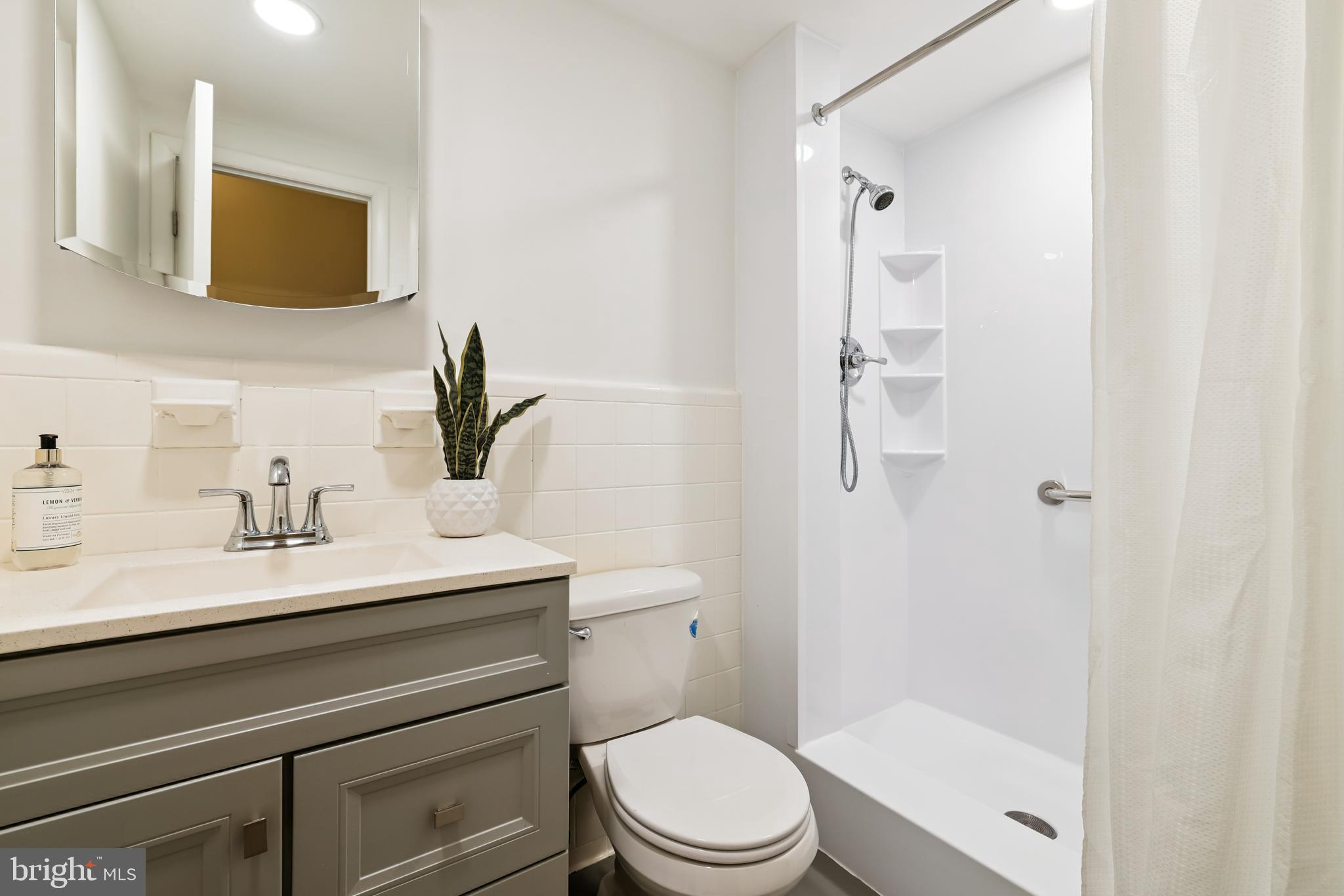 4800 Chevy Chase Drive, Unit 101 Chevy Chase, MD 20815 - Photo 9 of 17 a bathroom with a granite countertop sink toilet a mirror and shower