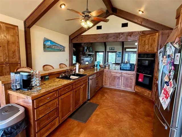 a large kitchen with stainless steel appliances granite countertop a sink and cabinets
