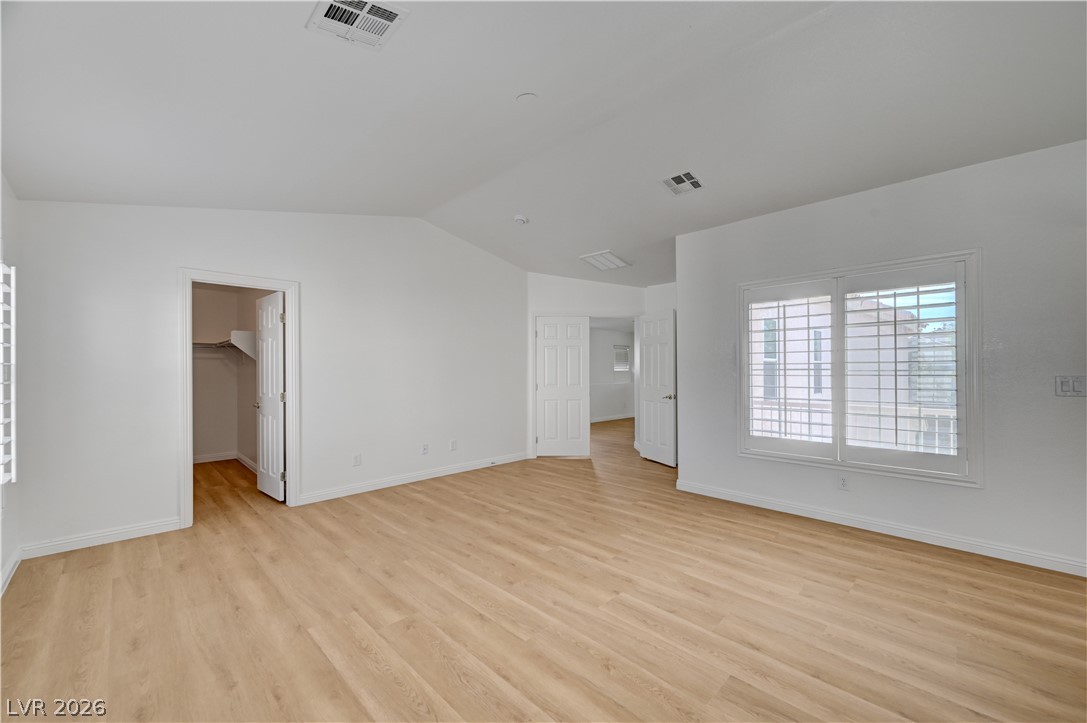 8918 Houston Ridge Avenue Las Vegas, NV 89178 - Photo 19 of 35 A spacious room presents light wood-like flooring and multiple windows with white plantation shutters.