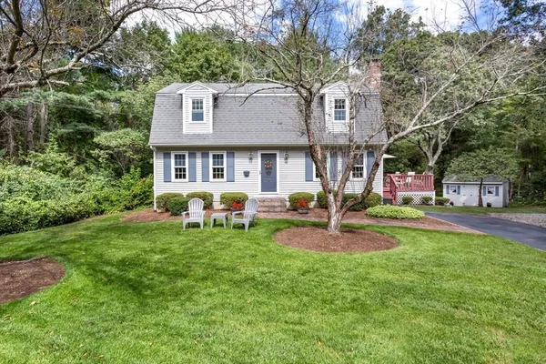 a front view of a house with garden and trees