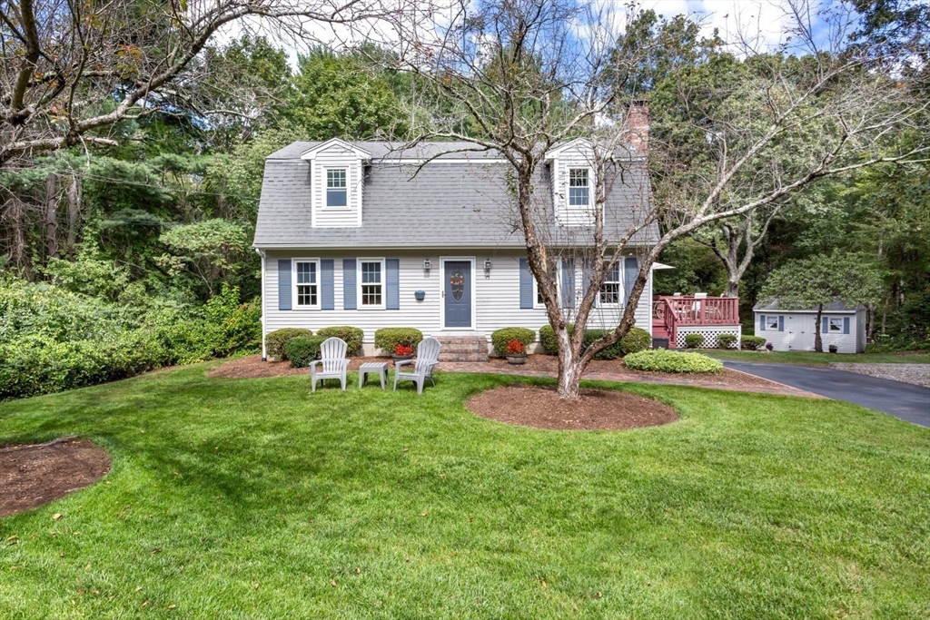 a front view of a house with garden and trees
