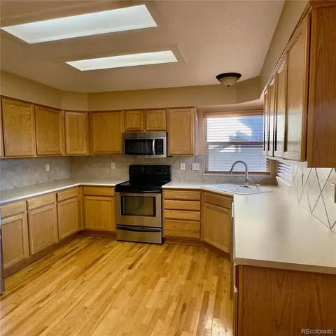 a kitchen with stainless steel appliances kitchen island granite countertop a sink a stove top oven a chimney and a counter space