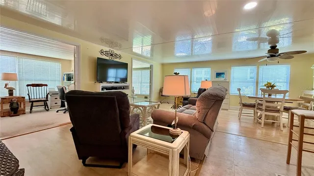 a living room with furniture a flat screen tv and kitchen view