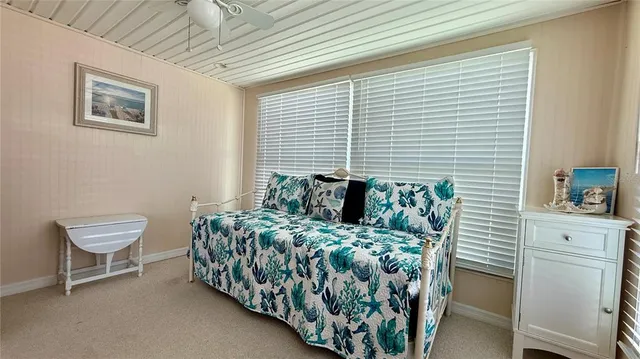 a bed sitting in a bedroom next to a window and a chair