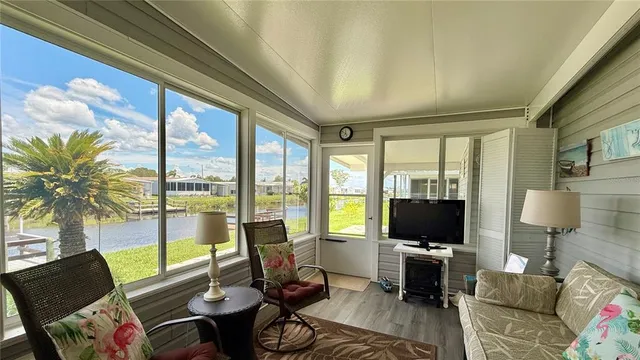a living room with furniture a flat screen tv and a floor to ceiling window