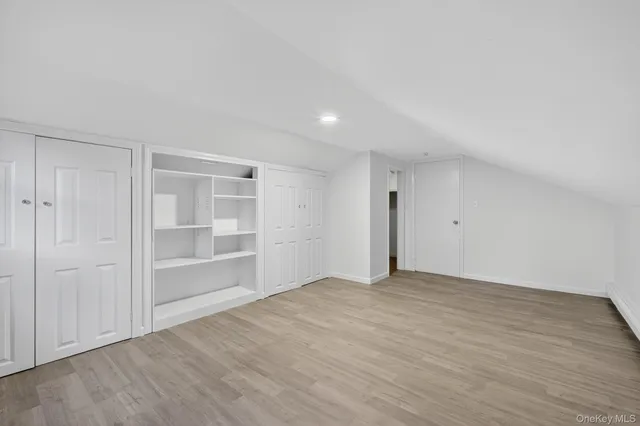 a view of an empty room with wooden floor and closet