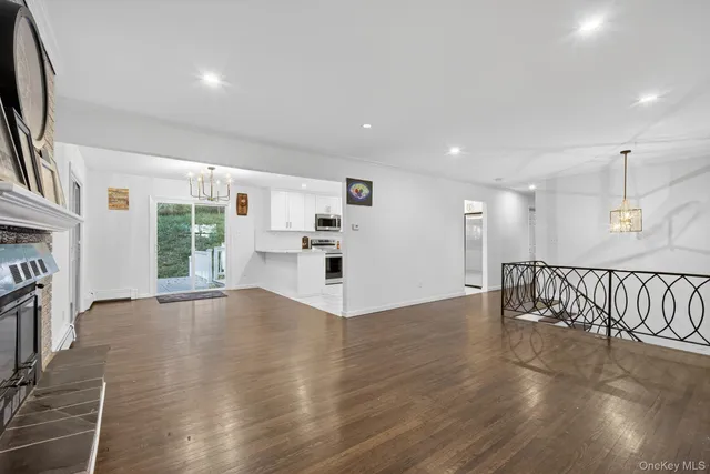 an empty room with wooden floor fireplace and windows