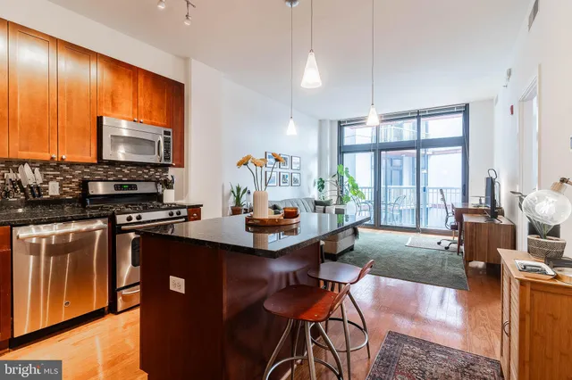 a living room with furniture kitchen area and large windows