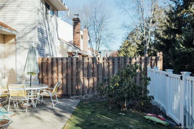 a backyard of a house with table and chairs and a large tree
