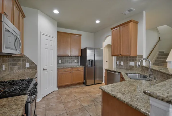a kitchen with stainless steel appliances granite countertop a sink stove and refrigerator