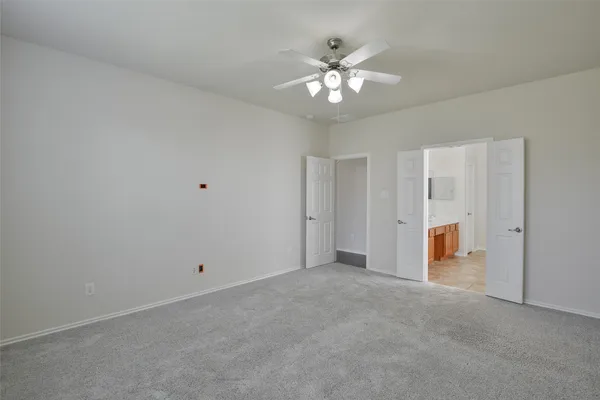 a view of an empty room with chandelier fan