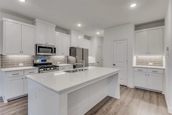 a kitchen with a sink a stove a refrigerator and white cabinets
