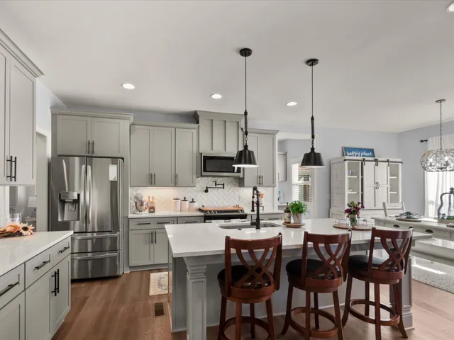a kitchen with stainless steel appliances a dining table chairs refrigerator and cabinets