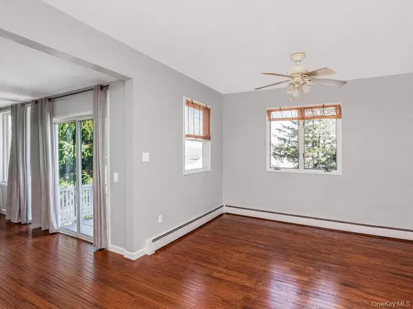 an empty room with wooden floor chandelier fan and windows