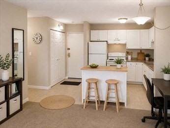 46 Cochituate Road, Unit 203 Framingham, MA 01701 - Photo 2 of 5 a kitchen with stainless steel appliances a dining table chairs refrigerator and sink