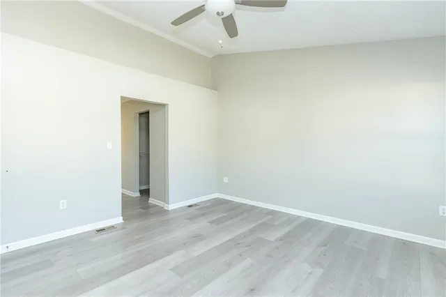 an empty room with a ceiling fan and wooden floor