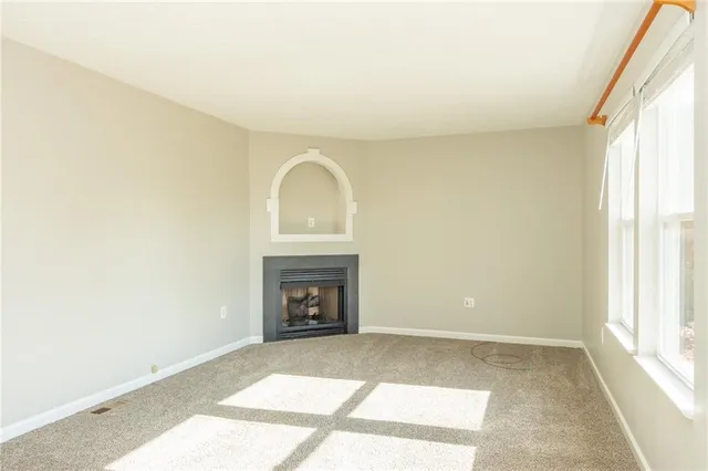 a view of an empty room with a fireplace and a window