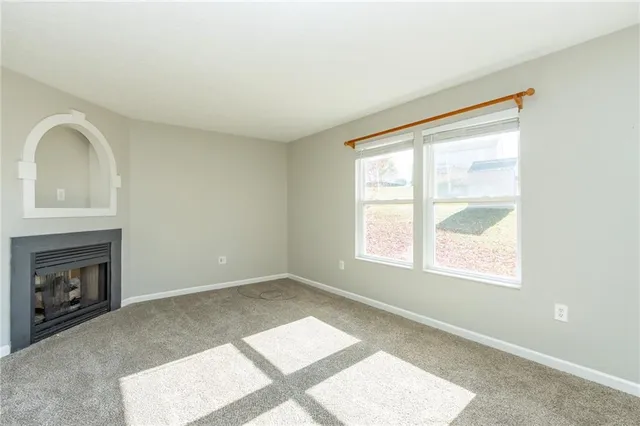 a view of an empty room with a window and fireplace