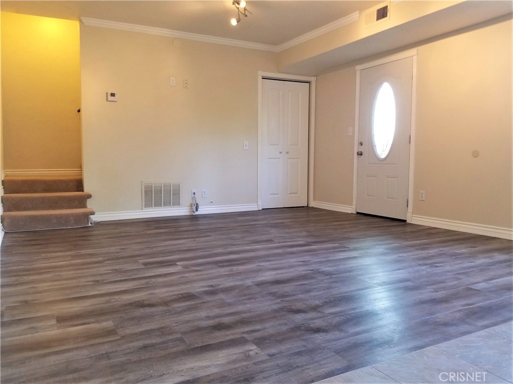 an empty room with wooden floor and mirror