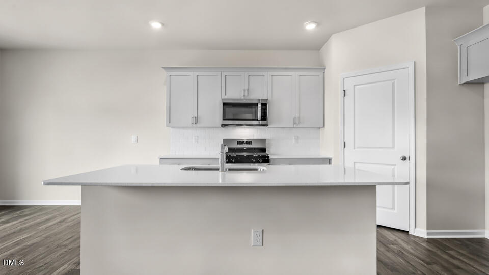 1277 Pavo Path Wendell, NC 27591 - Photo 9 of 53 a kitchen with stainless steel appliances a stove a microwave and white cabinets