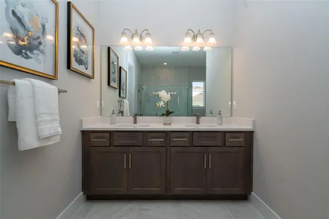 a bathroom with a granite countertop double vanity sink and a mirror