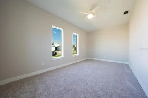 an empty room with windows and ceiling fan