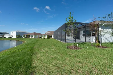 a view of a house with a big yard potted plants and large tree