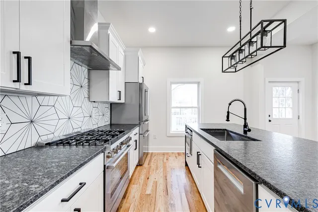 a kitchen with stainless steel appliances granite countertop a sink stove cabinets and refrigerator