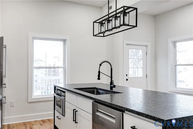 an outdoor kitchen with granite countertop a sink dining table and a window