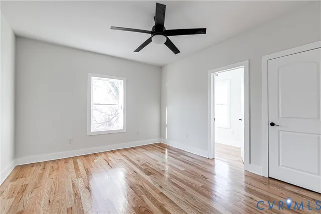 a view of empty room with wooden floor and fan