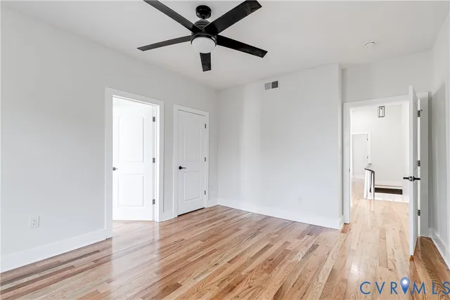 an empty room with wooden floor and a ceiling fan