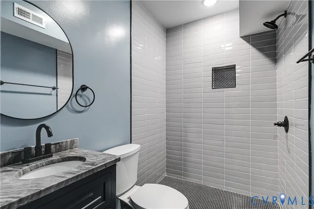 a bathroom with a granite countertop toilet sink and mirror