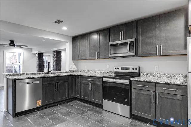 a kitchen with stainless steel appliances granite countertop wooden cabinets and a stove top oven