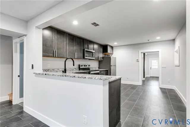 a kitchen with stainless steel appliances granite countertop a sink a stove a refrigerator a microwave and cabinets