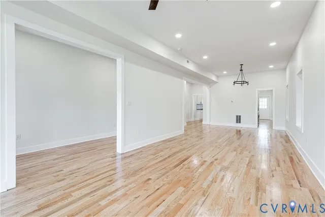 a view of a hallway with wooden floor and a ceiling fan
