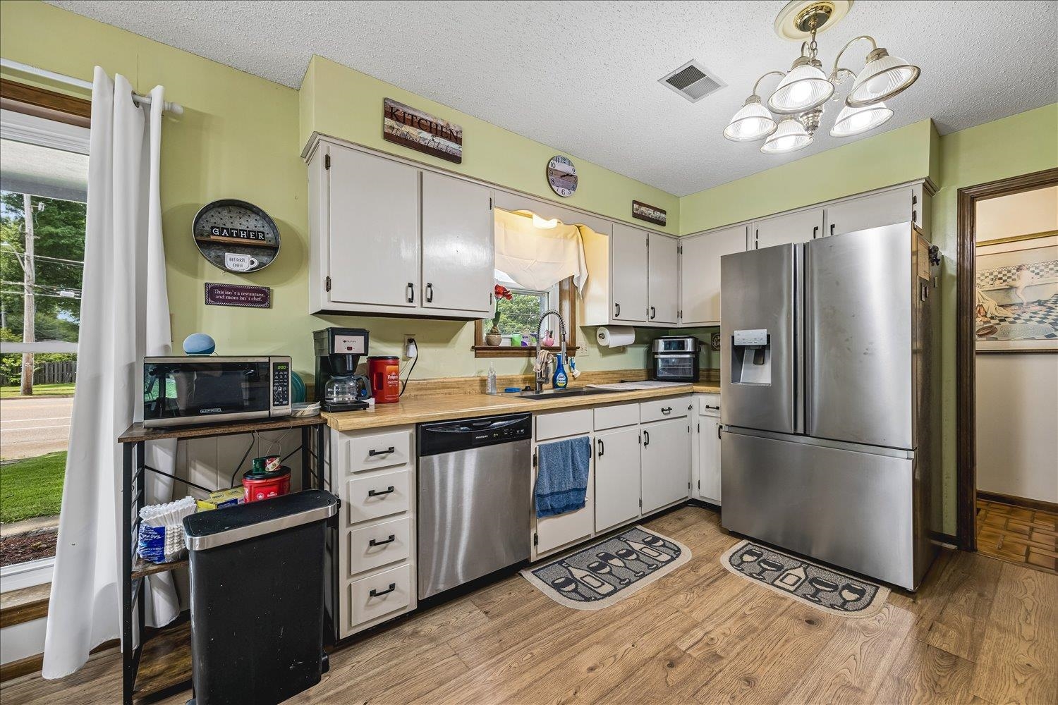 3284 Altruria Road Bartlett, TN 38134 - Photo 13 of 28 Kitchen featuring wood-finish flooring, white cabinetry, a stainless steel refrigerator, a stainless steel dishwasher, and a double-basin sink
