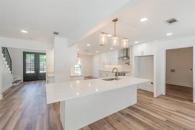 a large room with kitchen island a sink stainless steel appliances and wooden floor