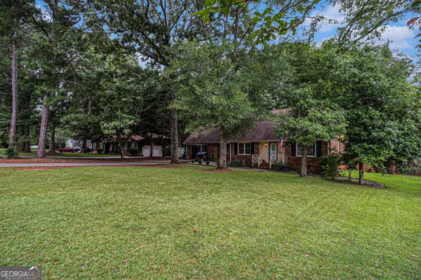 a view of a house with a big yard and large trees