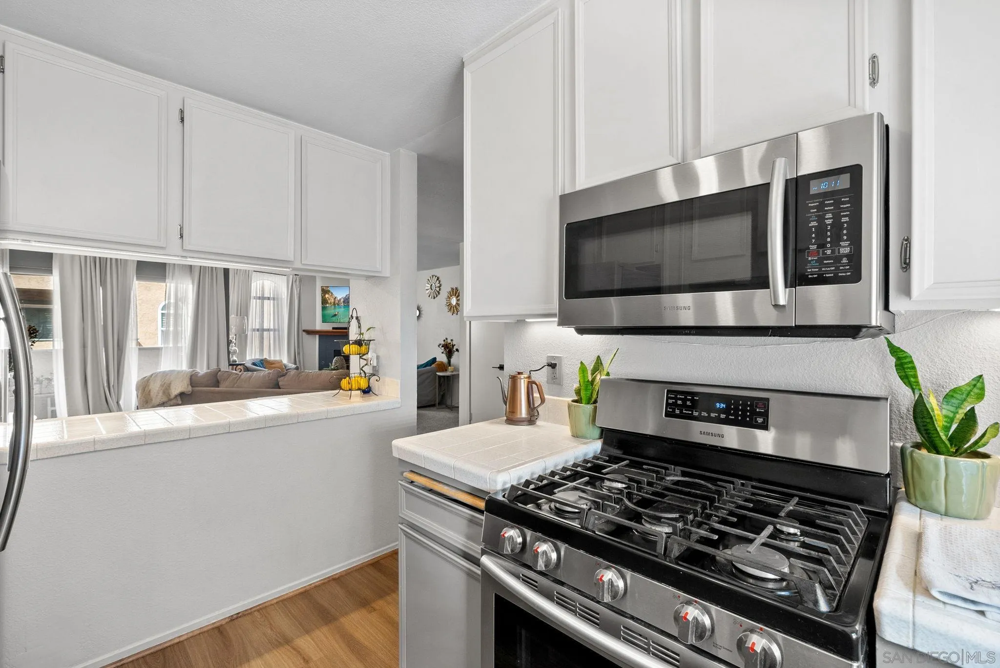 10790 Riderwood Terrace, Unit B Santee, CA 92071 - Photo 8 of 24 a kitchen with stainless steel appliances a stove a microwave a sink and white cabinets