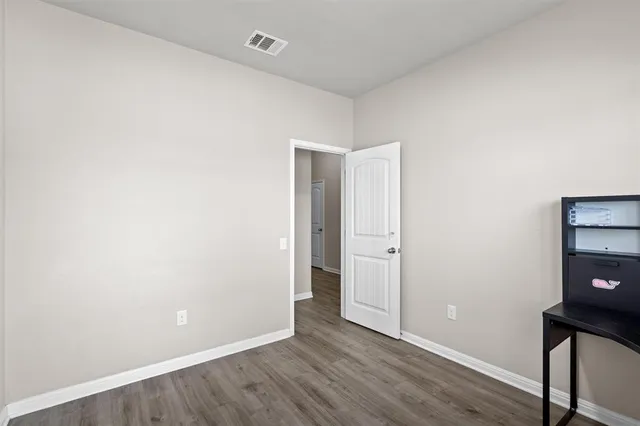 a view of an empty room with wooden floor and closet
