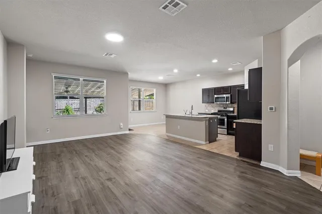 an open kitchen with a refrigerator and a stove top oven