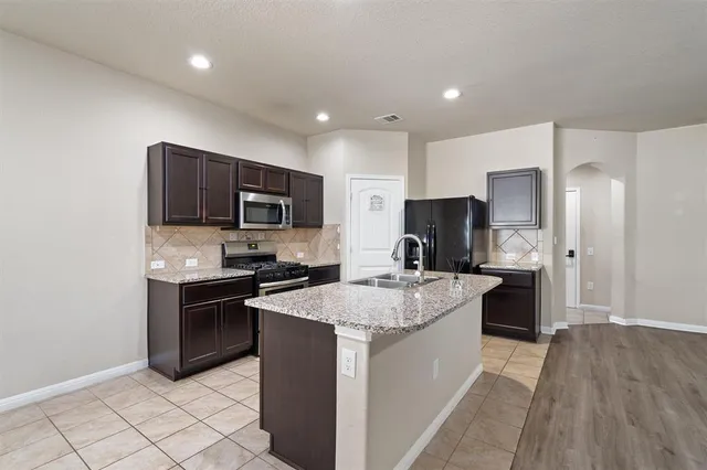 a kitchen with stainless steel appliances granite countertop a refrigerator stove microwave and sink