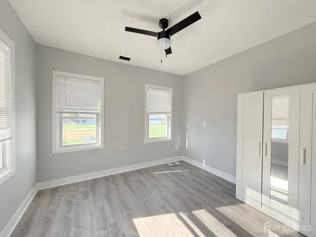 a view of empty room with wooden floor and fan