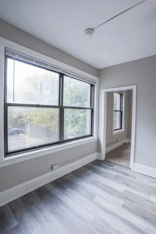 a view of an empty room with a window and wooden floor