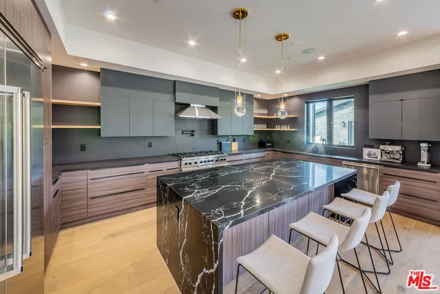 a kitchen with kitchen island a counter top space a sink stainless steel appliances and cabinets