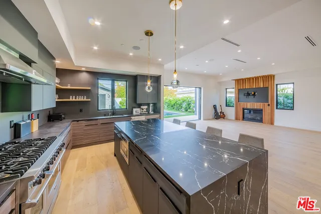 a large kitchen with kitchen island a large counter space a sink a window and stainless steel appliances