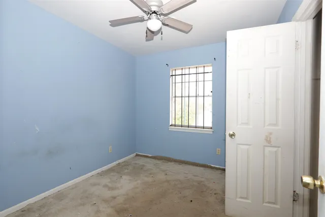 an empty room with windows and fan