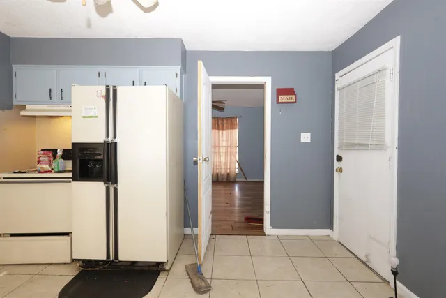 a view of a kitchen with refrigerator and white cabinets
