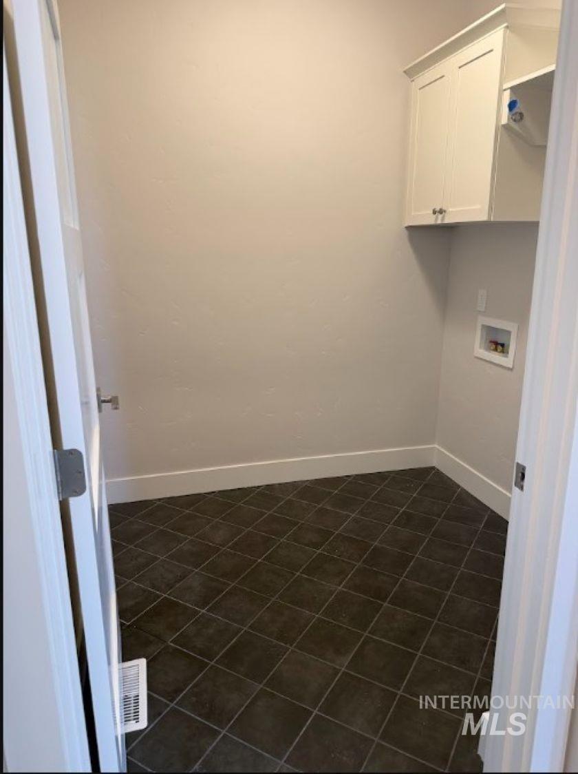 665 West Wrangler Street Meridian, ID 83646 - Photo 12 of 18 Utility room featuring dark square tile flooring, light-toned walls, white baseboards, and built-in upper cabinetry with silver hardware