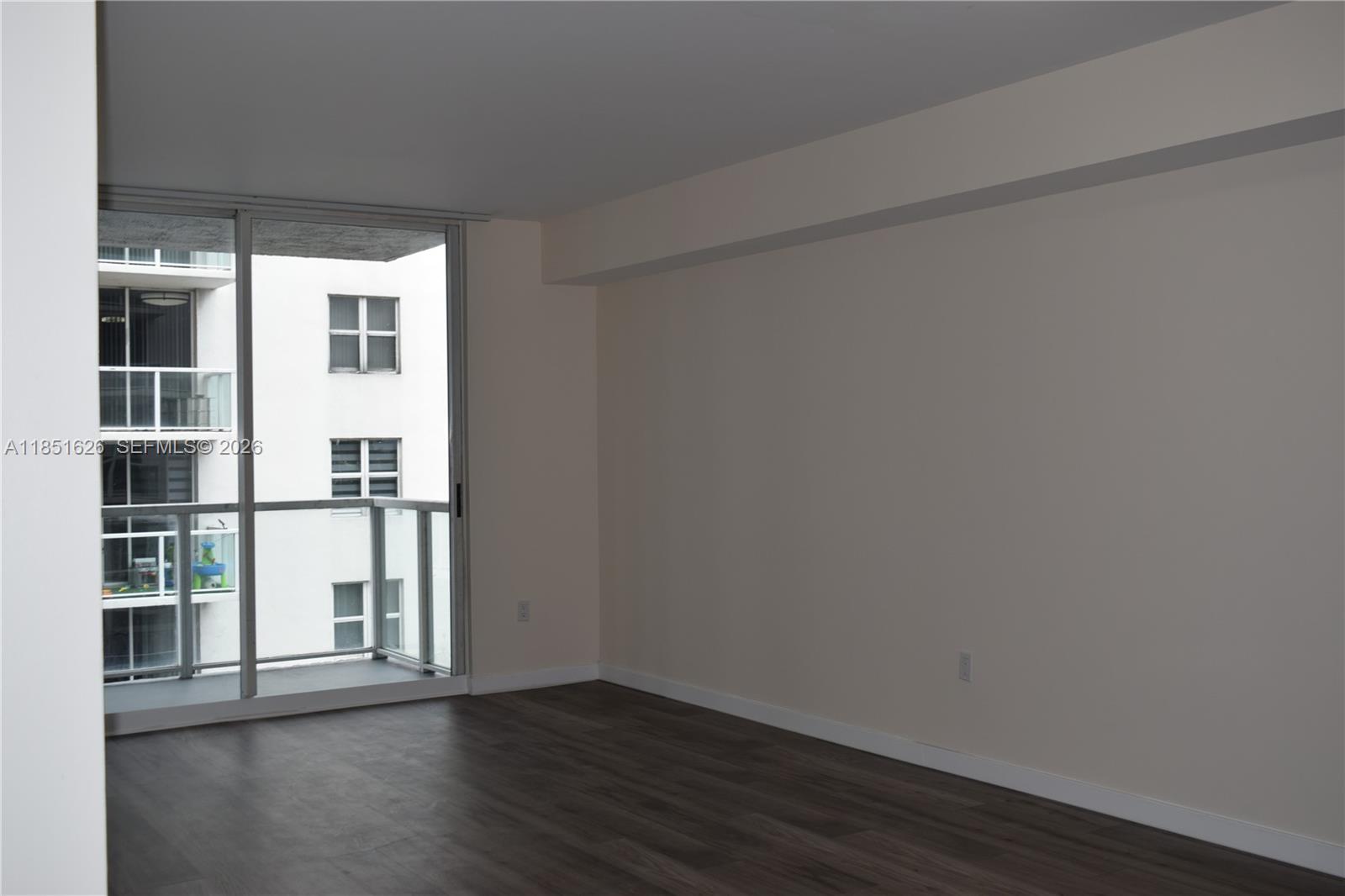 5091 Northwest 7th Street, Unit 711 Miami, FL 33126 - Photo 13 of 72 a view of an empty room with wooden floor and a window